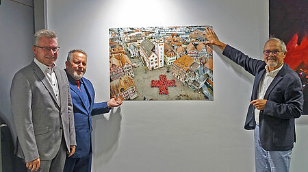 Bildübergabe_DRK_LRA_1.jpg Drei Personen, Wandbild des Mosbacher Marktplatzes
