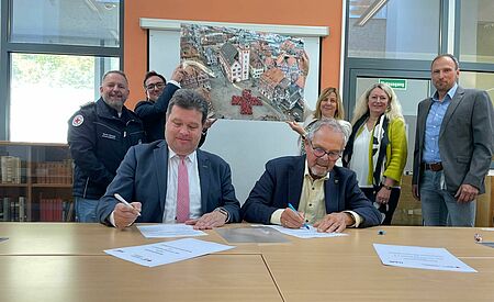 Bildungspartnerschaft2 Schulleiter Jochen Herkert und DRK-Präsident Gerhard Lauth unterzeichneten an einem Tisch sitzend eine Bildungspartnerschaft zwischen NKG und DRK-Kreisverband Mosbach. Bild: DRK