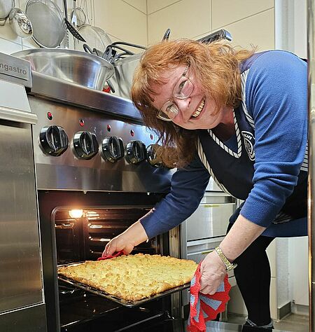 Neuer_Ofen_1_26.jpg Eine Frau holt einen Kuchen aus einem Backofen